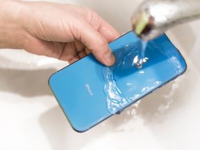 Čovek drži telefon ispod mlaza vode