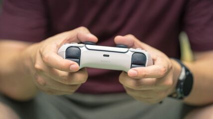Gejmer drži PlayStation kontroler u rukama