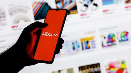 AliExpress logo na telefonu ispred stranice sa oglasima