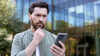 Zbunjen čovek gleda u telefon