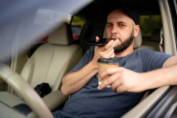 Muškarac u automobilu na spikerfonu