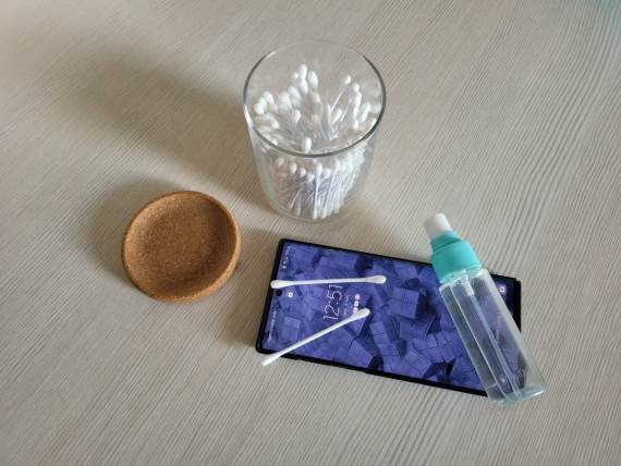 Telefon na stolu pored pakovanja štapića za uši i bočice alkohola